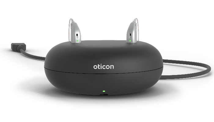 Oticon: Schwarzes rundes Ladegerät mit zwei Hörgeräten darin