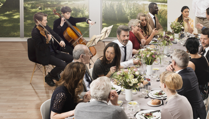 Oticon: Viele Menschen beim Tischgespräch und Musiker