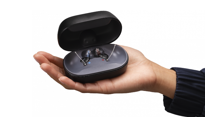 Oticon: Charger mit Hörgerät auf Hand