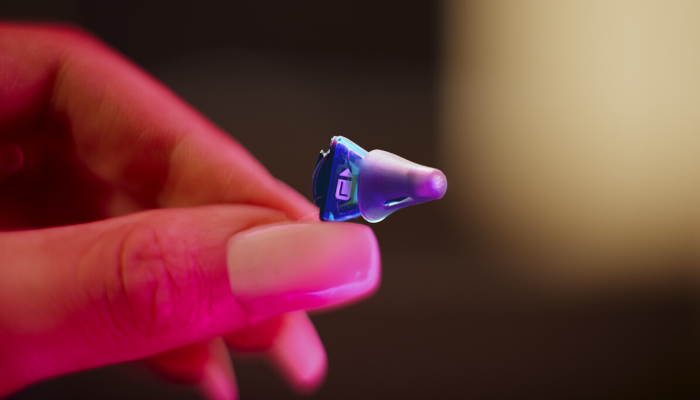 Signia: Kleines Standard-Im-Ohr-Hörgerät mit Dome in der Hand einer Frau