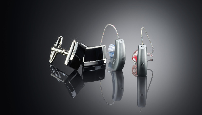 Widex: Zwei Hörgeräte neben zwei Manschettenknöpfen