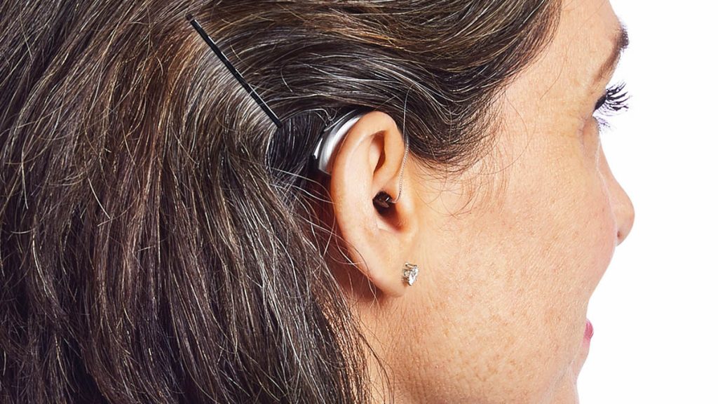 Silbernes Hinter-dem-Ohr-Hörgerät an einem Frauenohr