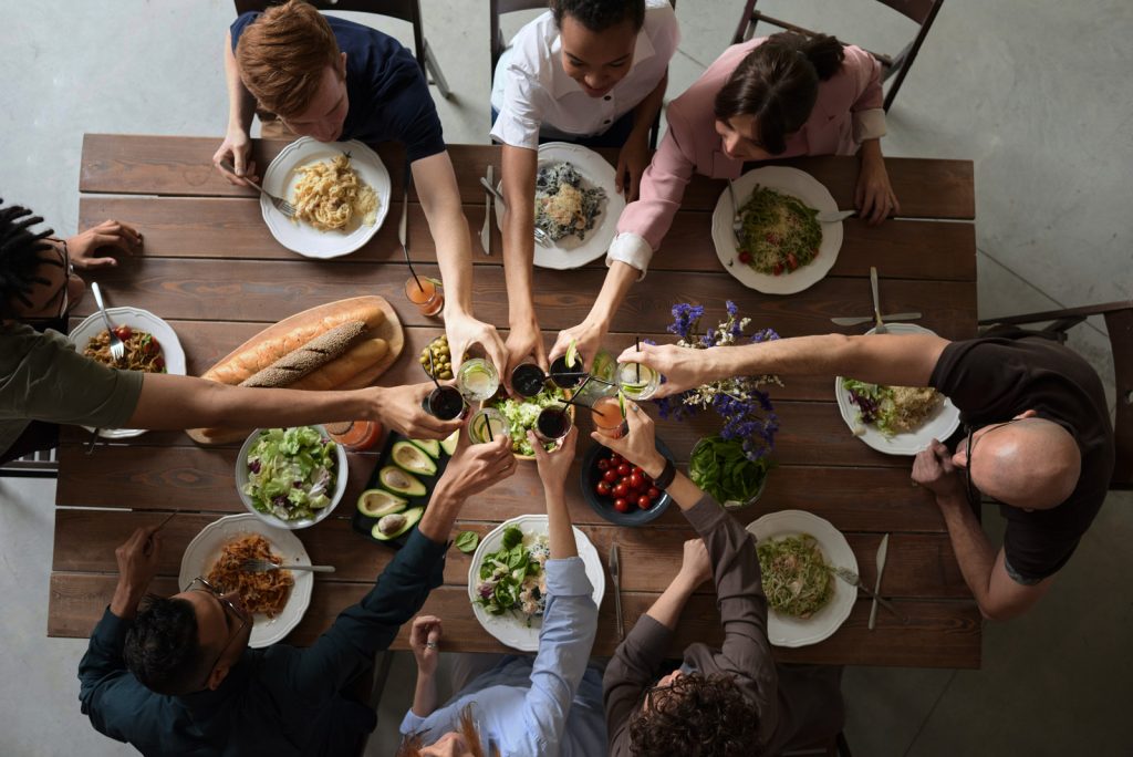 Symbolbild mit vielen Menschen an einem Tisch für die Wirkung von Spectral Speech von Unitron DX Hörgeräte im Ladegeräten.