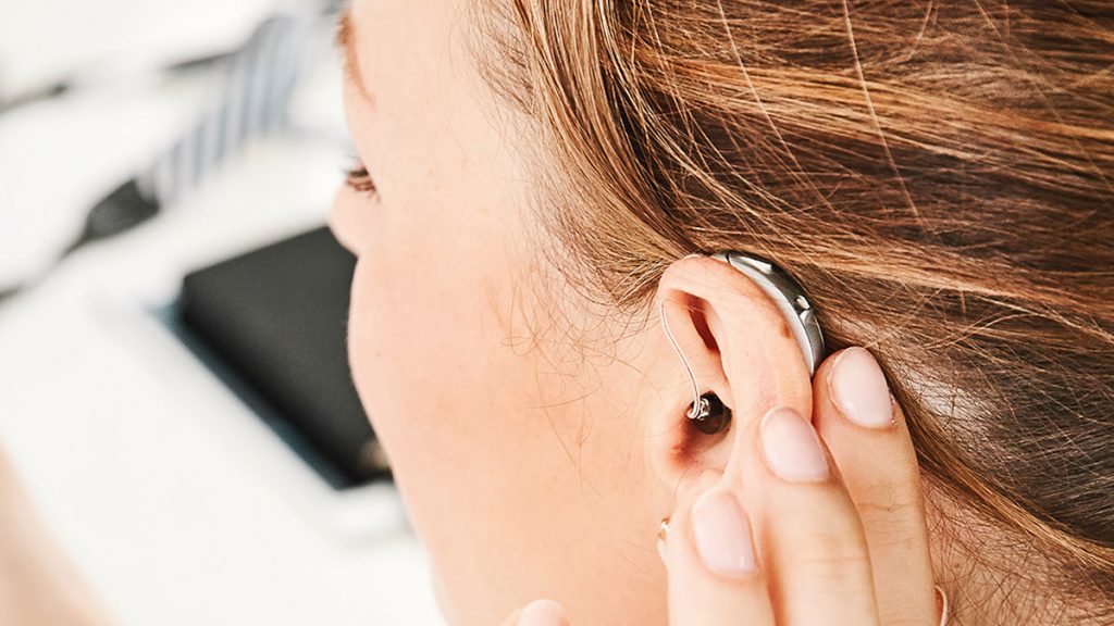 Frau berührt ein Hansaton Excite Pro Hörgerät