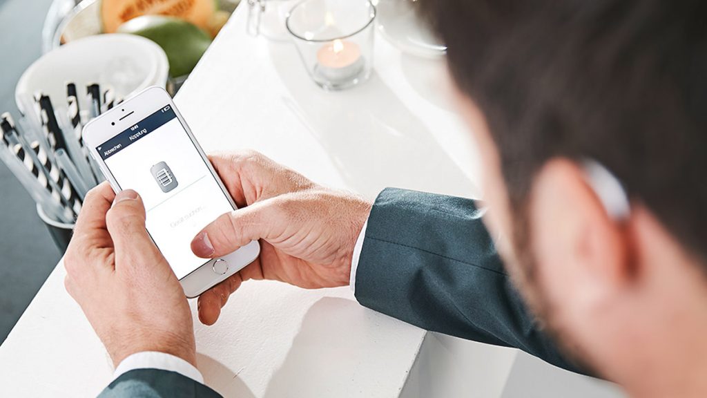 Ein Mann bedient eine Hörgeräte-App.