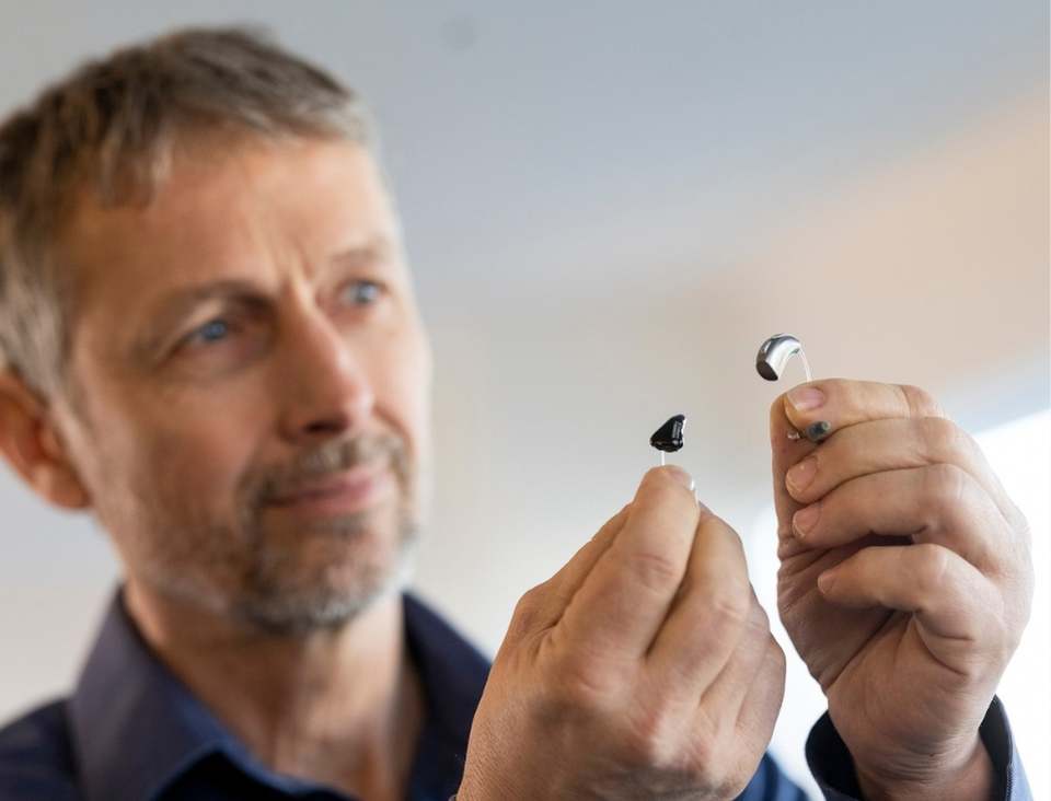 Hörgeräte Preise: Was kosten Hörgeräte 2025? 10 Hörgeräte Preise: Ein Mann hält unterschiedliche Hörgeräte in den Händen.